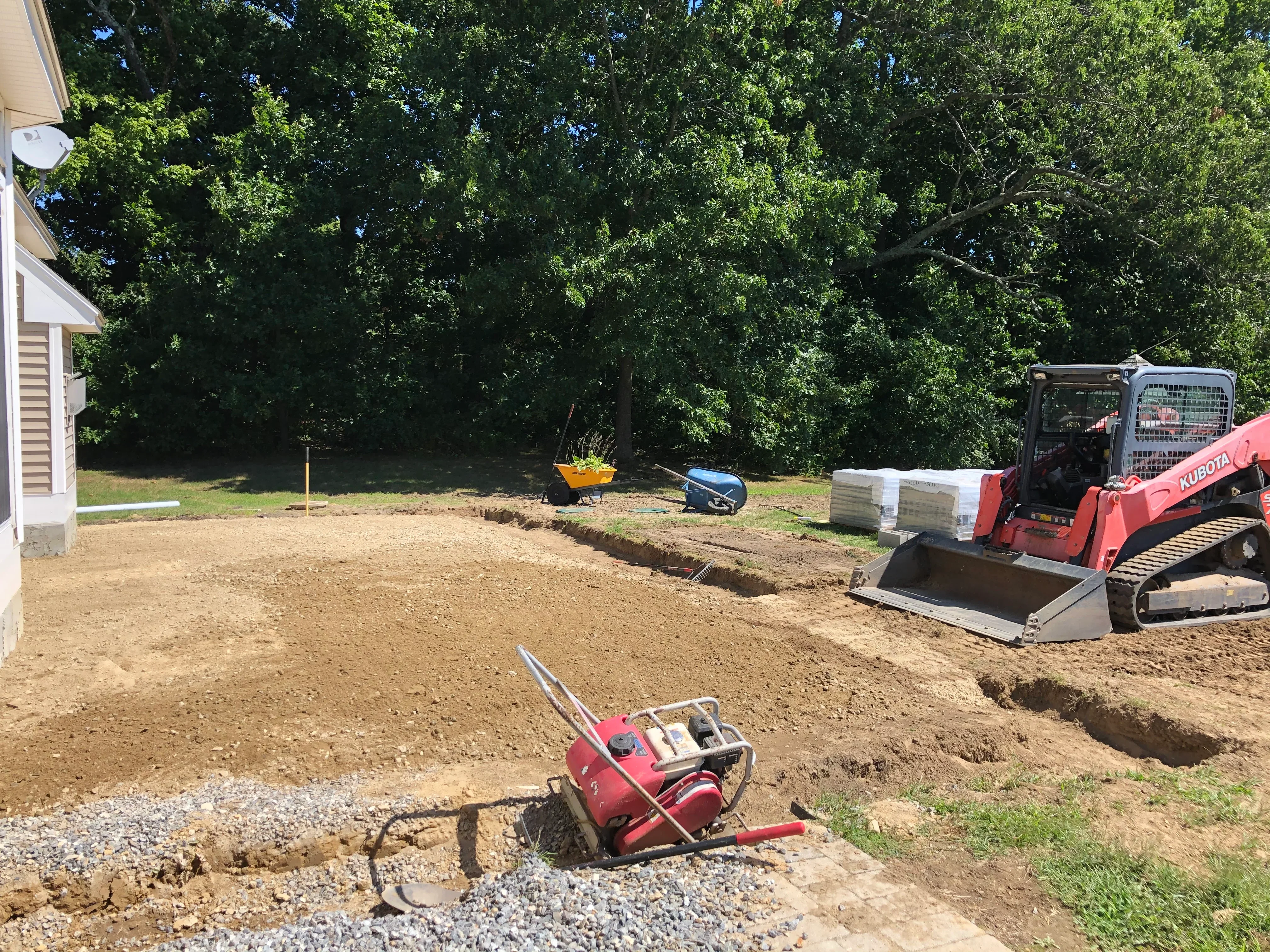 Skid steer loader and compactor on residential lot during grading and site preparation work