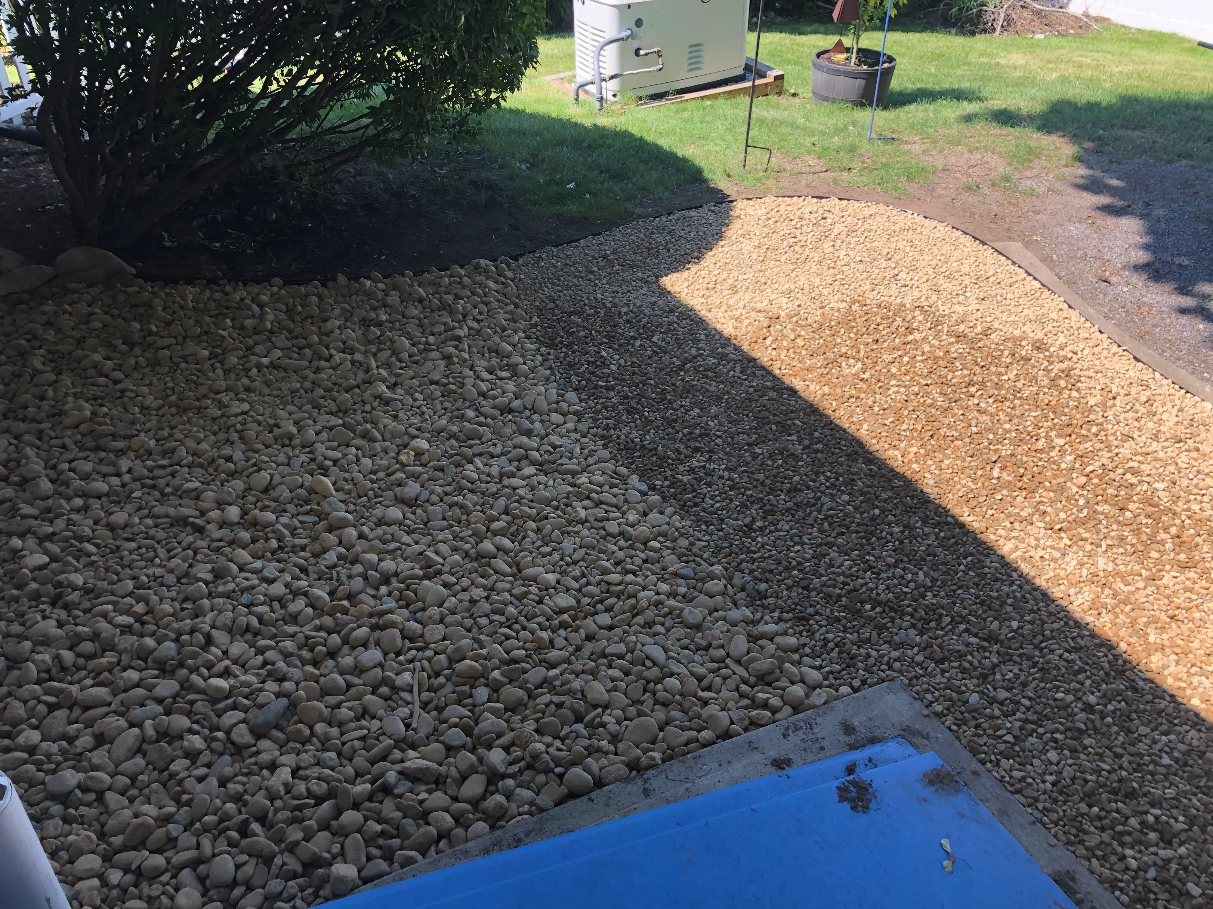 Hardscape installation with river rock, crushed stone, and pea gravel in defined zones