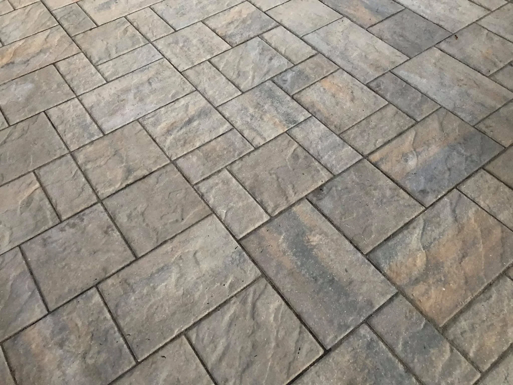 Herringbone pattern concrete pavers with tumbled finish and uniform grout joints