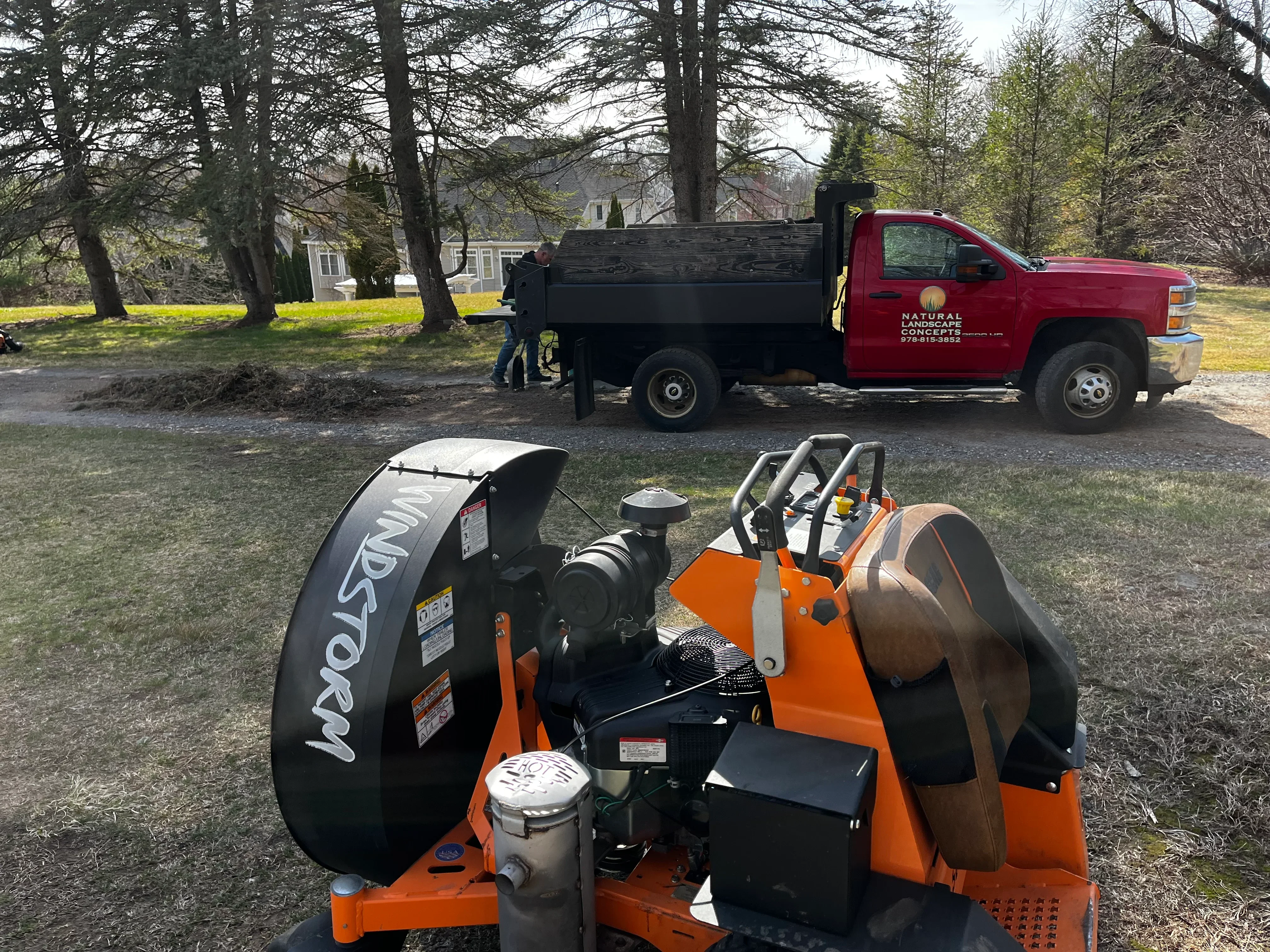 Wood chipper and dump truck removing debris from residential property with mature trees