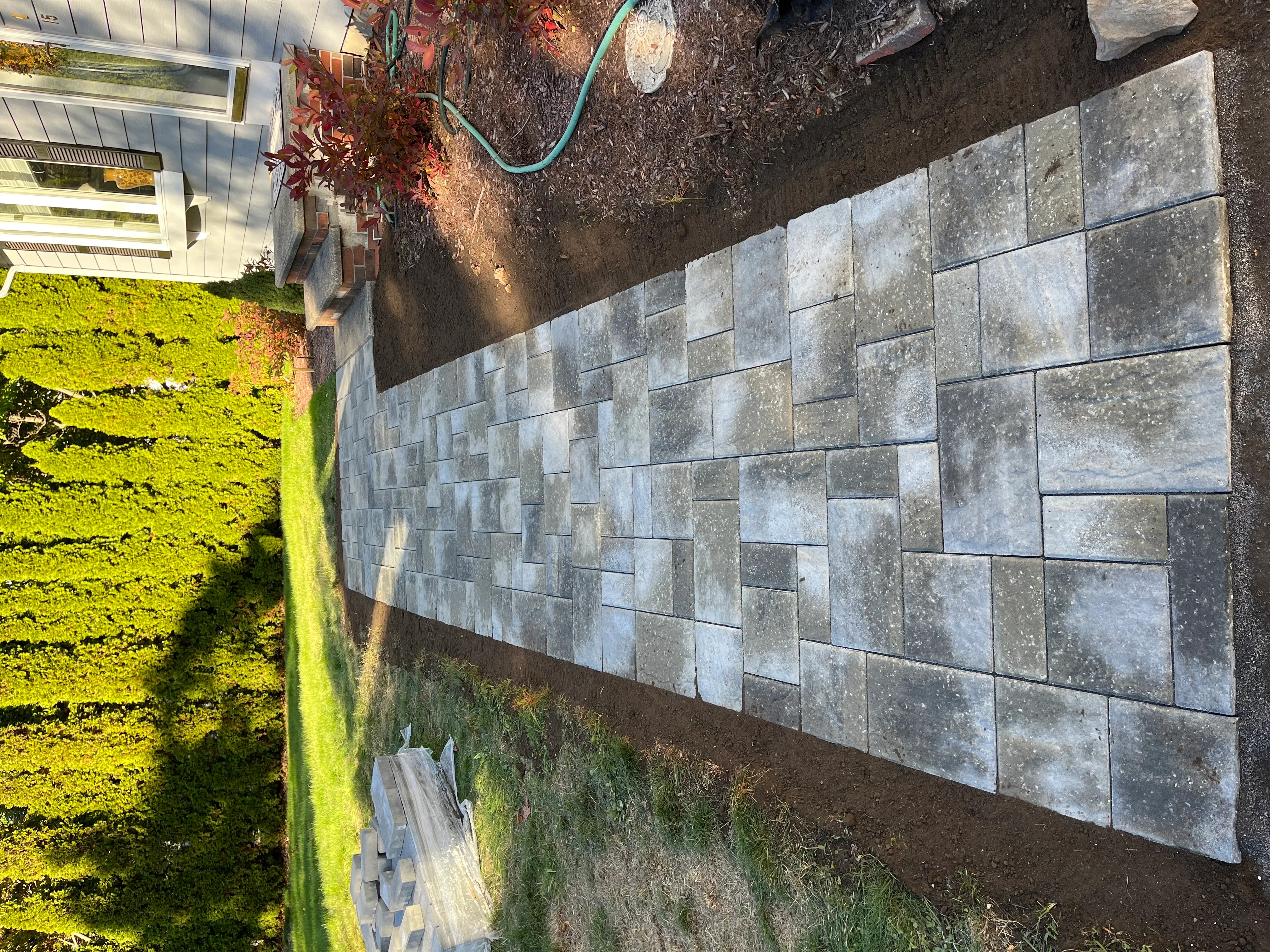 Gray concrete permeable pavers installed in running bond pattern along residential pathway