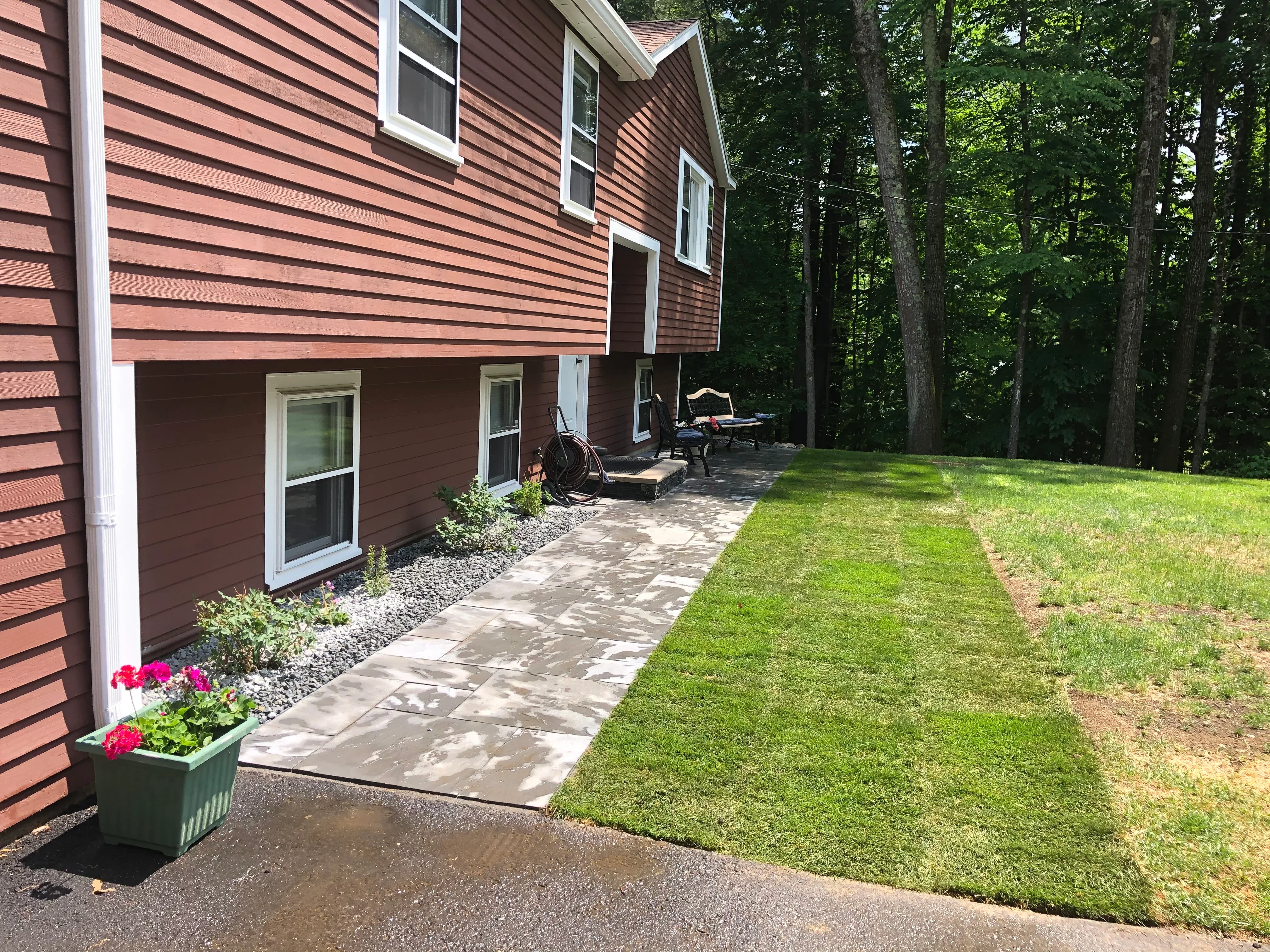 Flagstone patio pathway with gravel beds and newly seeded lawn beside residential home