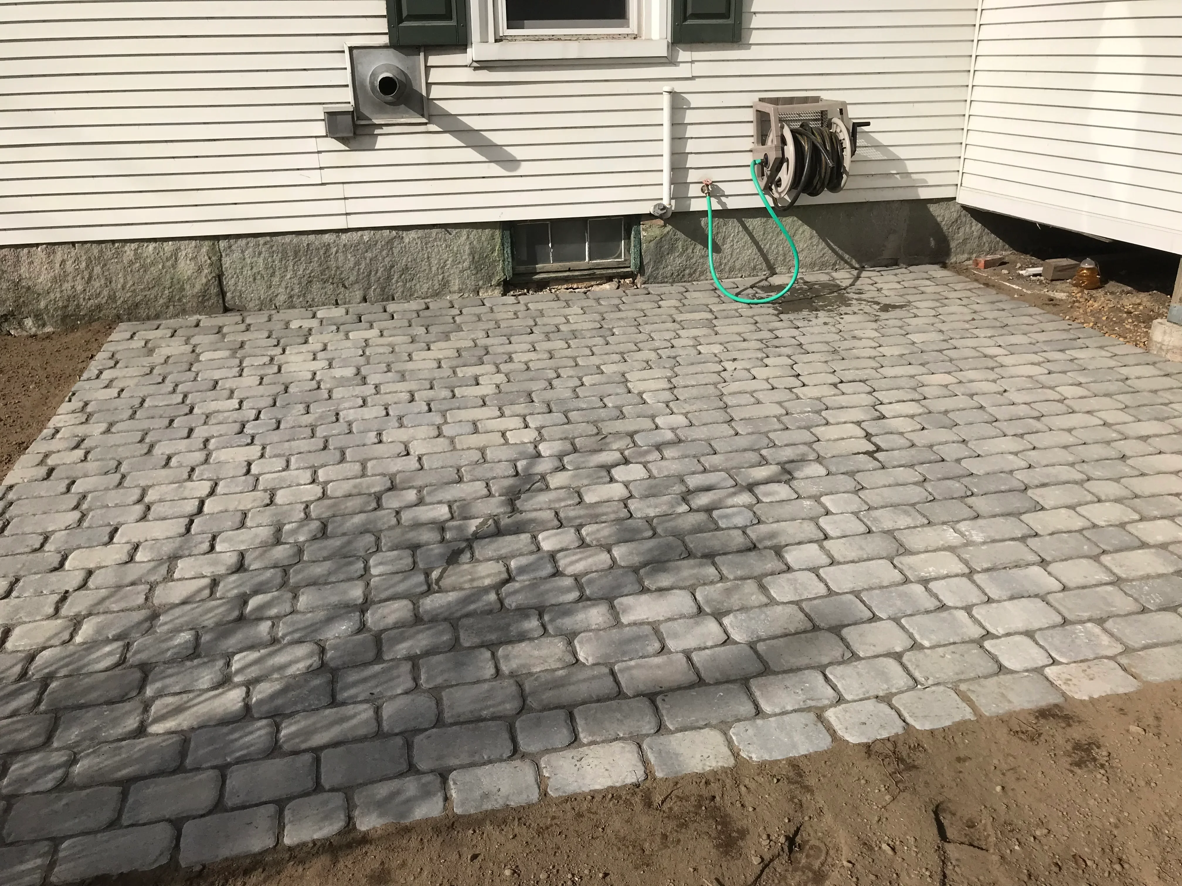 Herringbone permeable paver patio with concrete retaining wall and drainage system