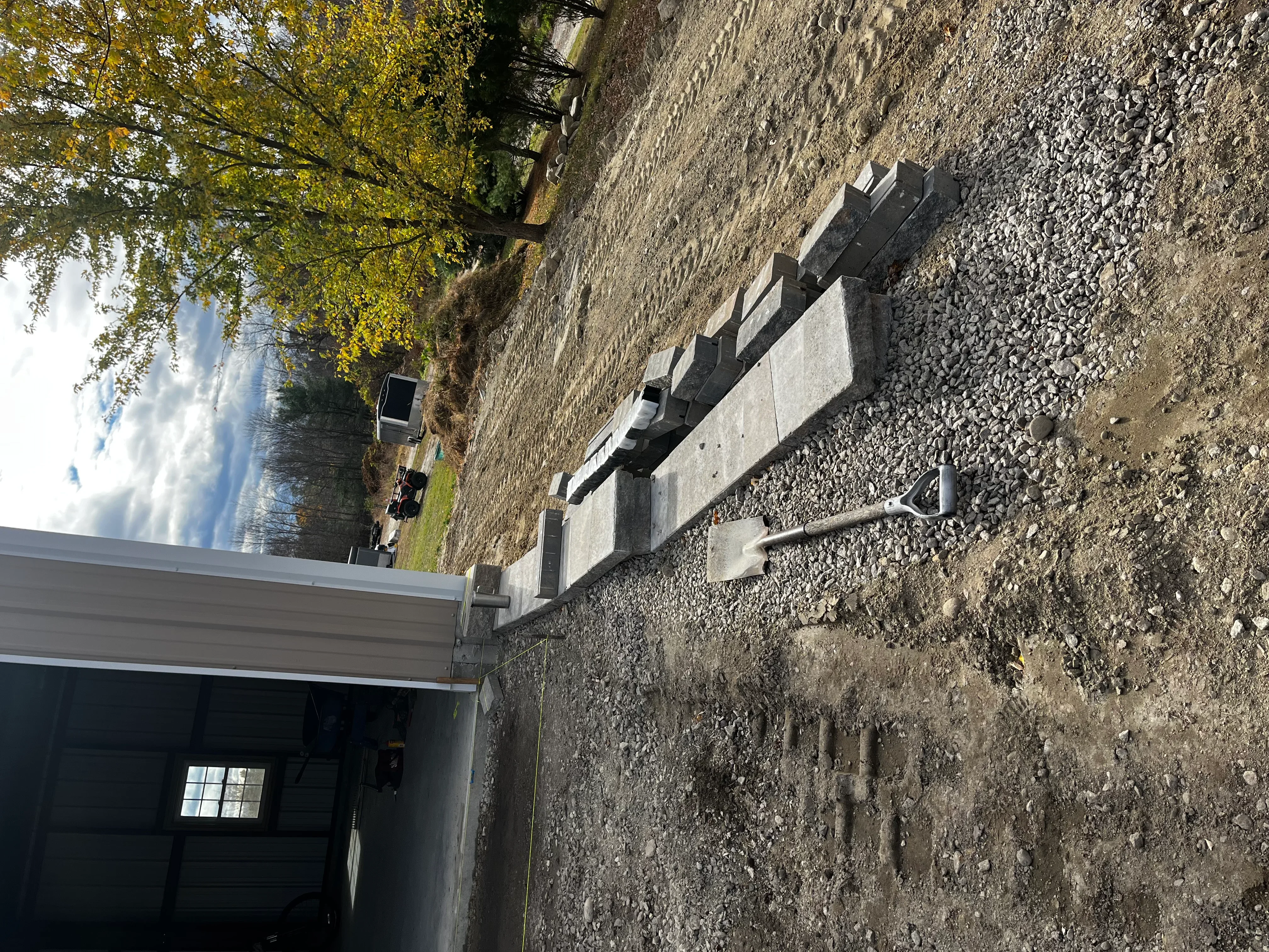 Concrete block retaining wall with drainage pipe and gravel backfill installation