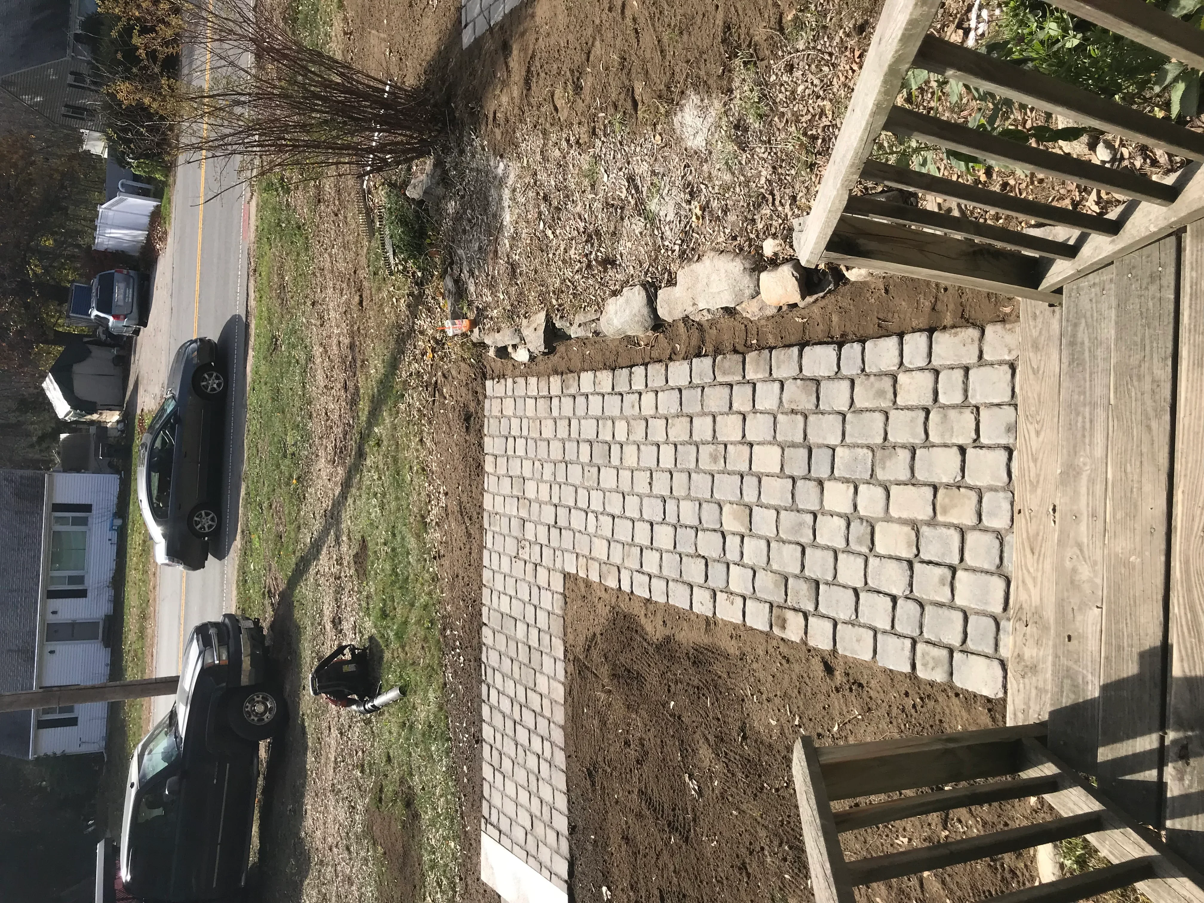 Concrete block retaining wall with uniform light blocks in running bond pattern, compacted soil base, adjacent to wooden deck
