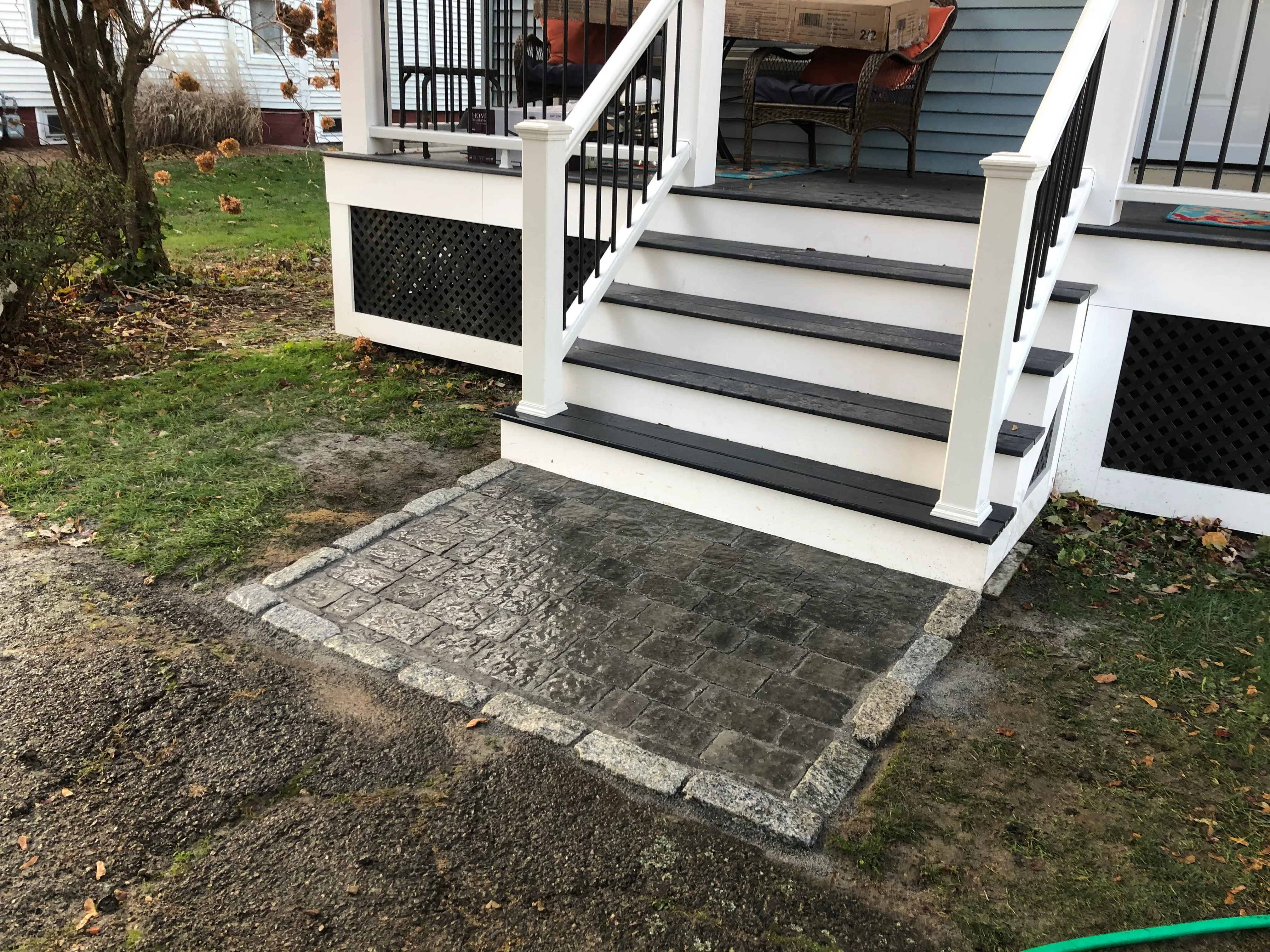 Paver walkway with granite border and black composite deck stairs with white railings