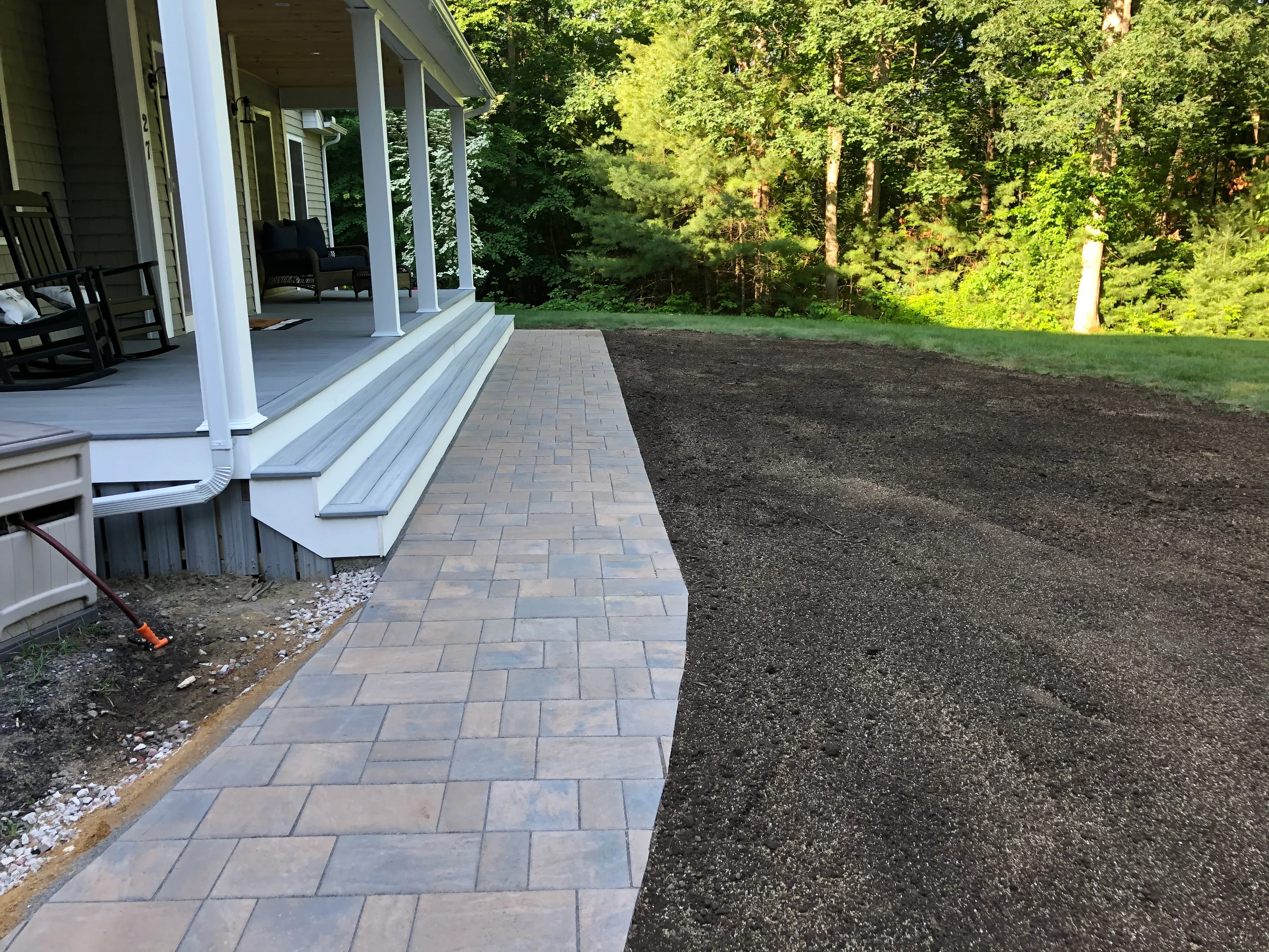 Gray paver patio in herringbone pattern with composite steps and mulched landscape beds