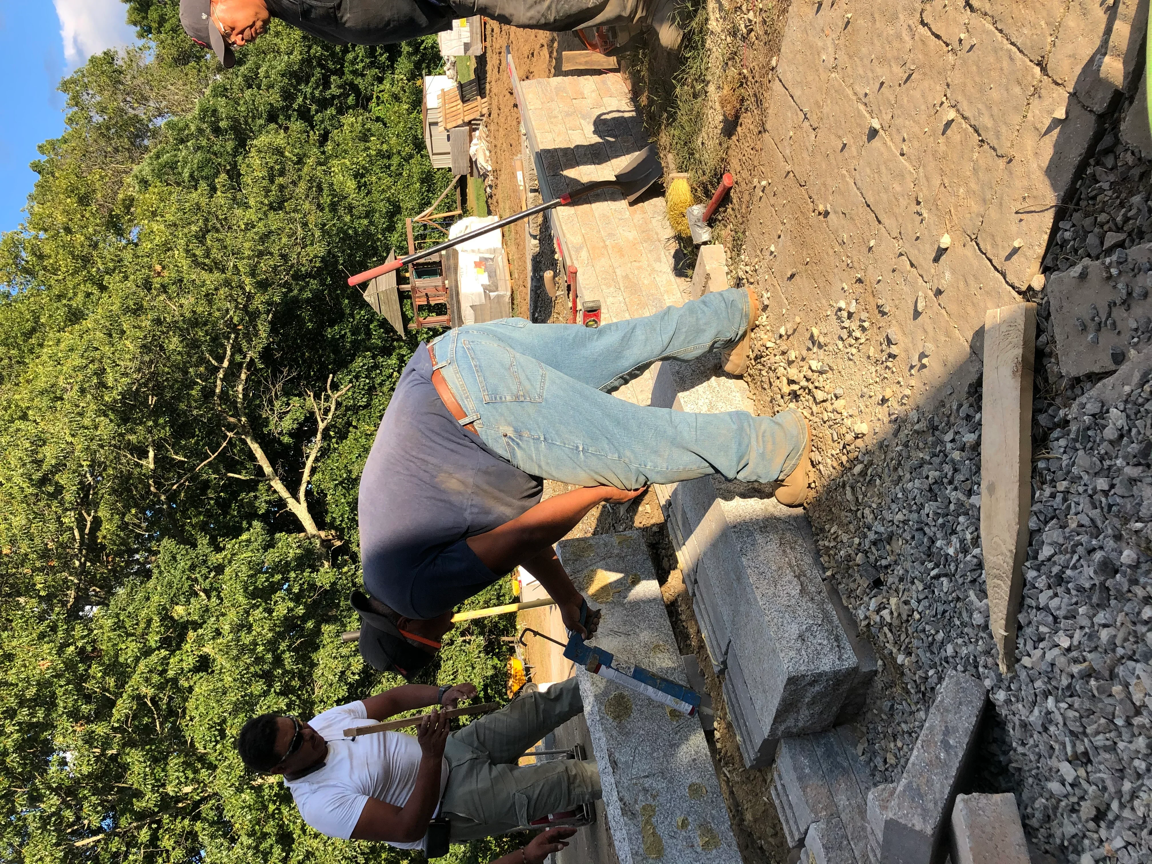 Concrete block retaining wall installation with gravel base and excavated site preparation
