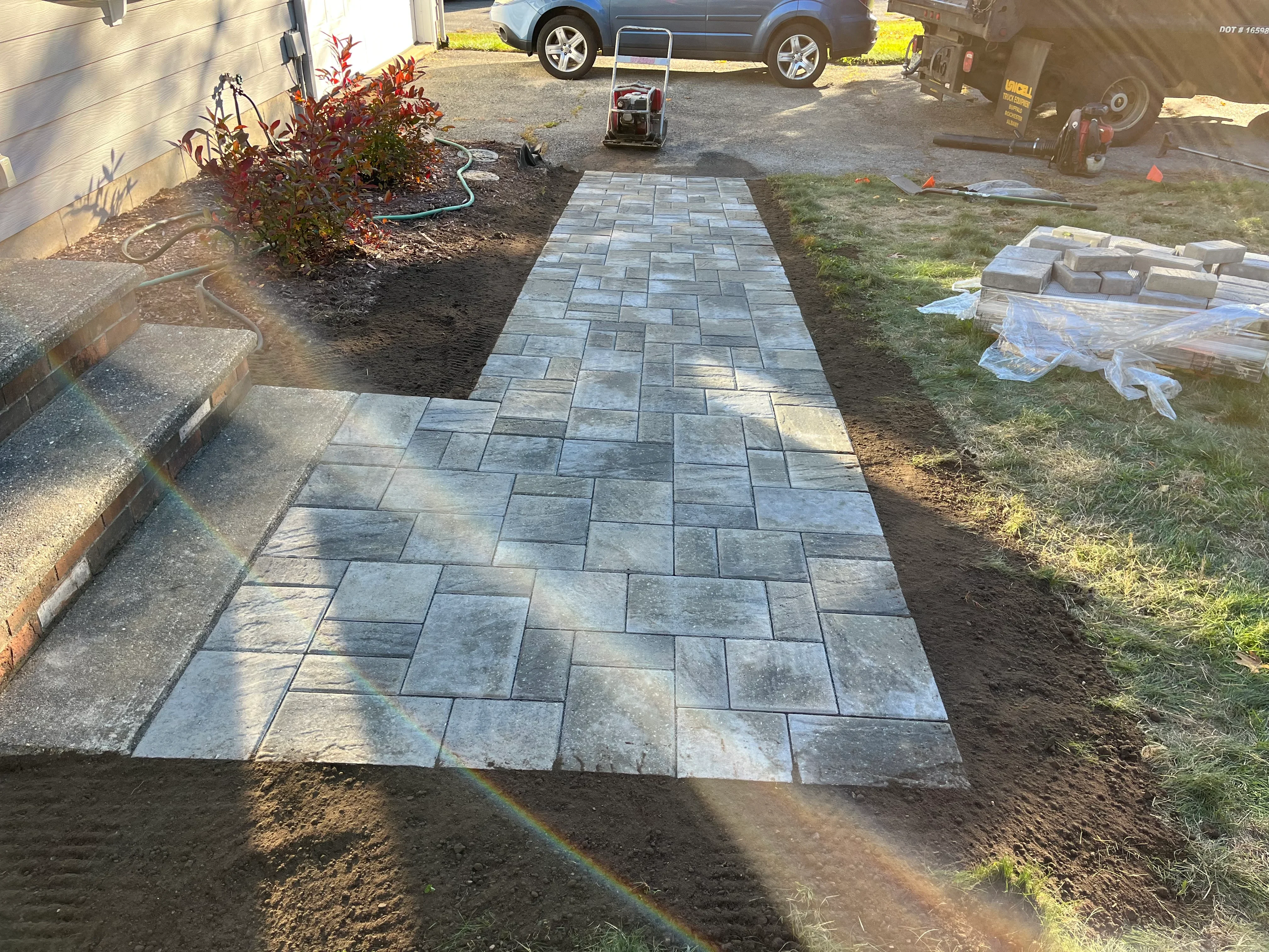 Gray concrete permeable pavers laid in running bond pattern on prepared base with landscape edging