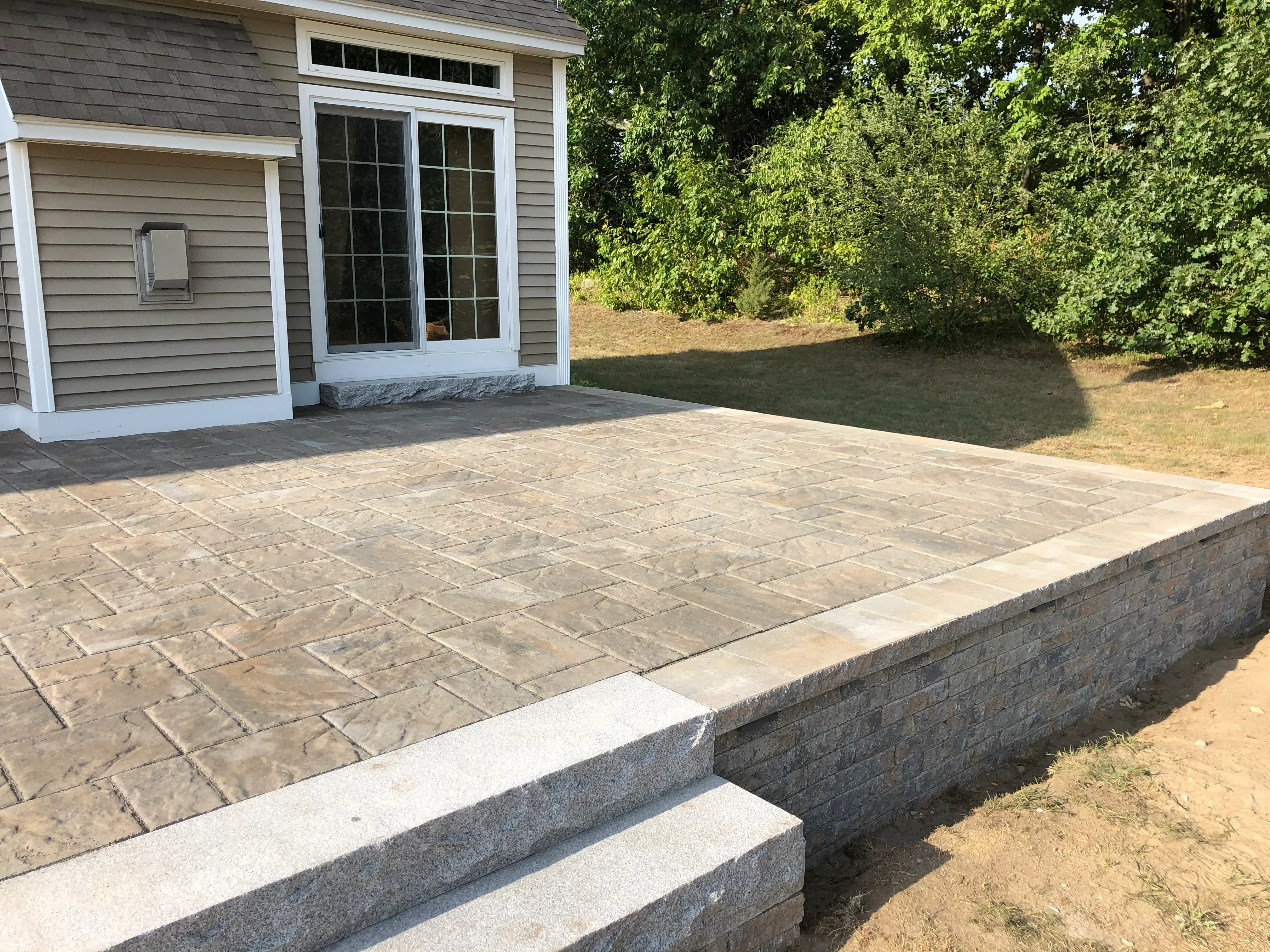 Stamped concrete patio with ashlar pattern and granite retaining wall with steps