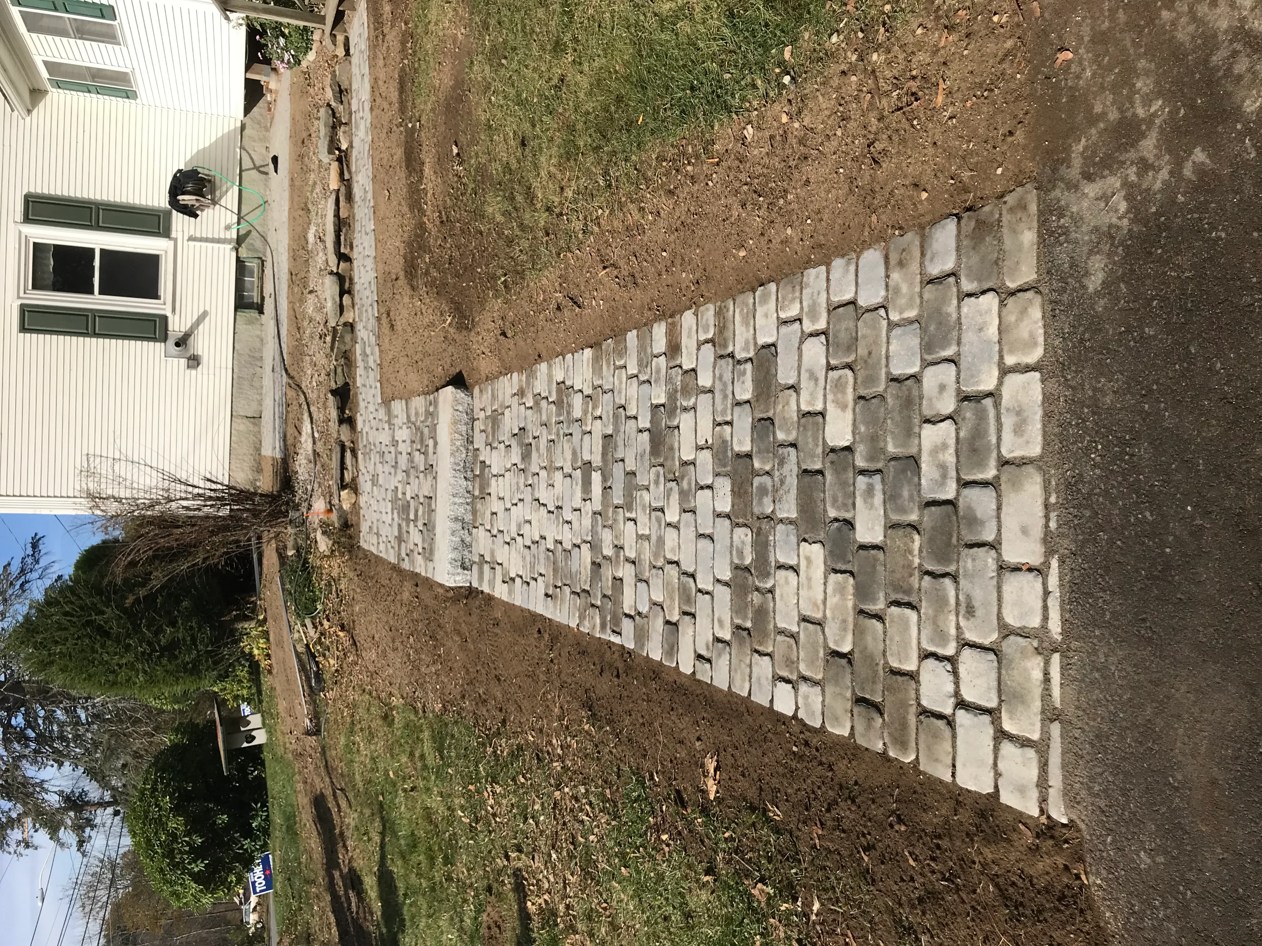 Concrete block retaining wall with stacked units and compacted soil backfill on sloped terrain