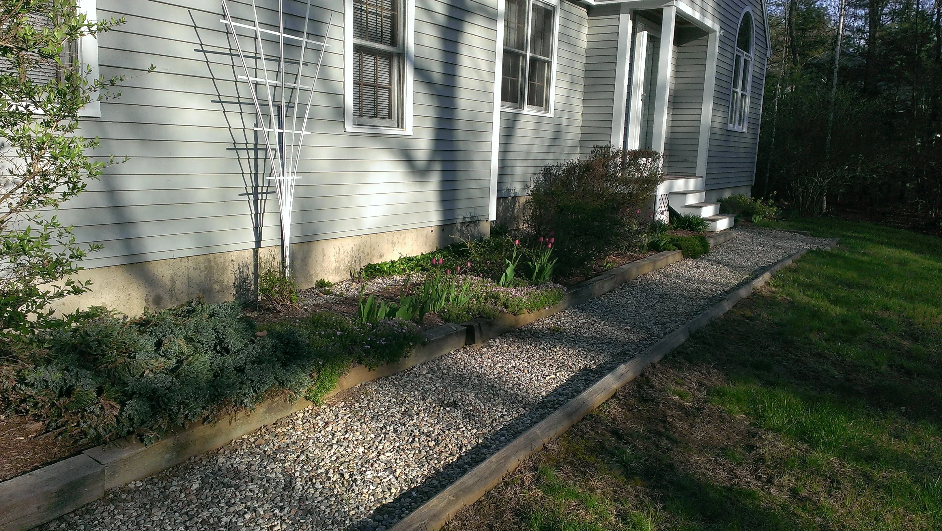 Foundation planting beds with gravel pathway, timber edging, ornamental grasses and shrubs