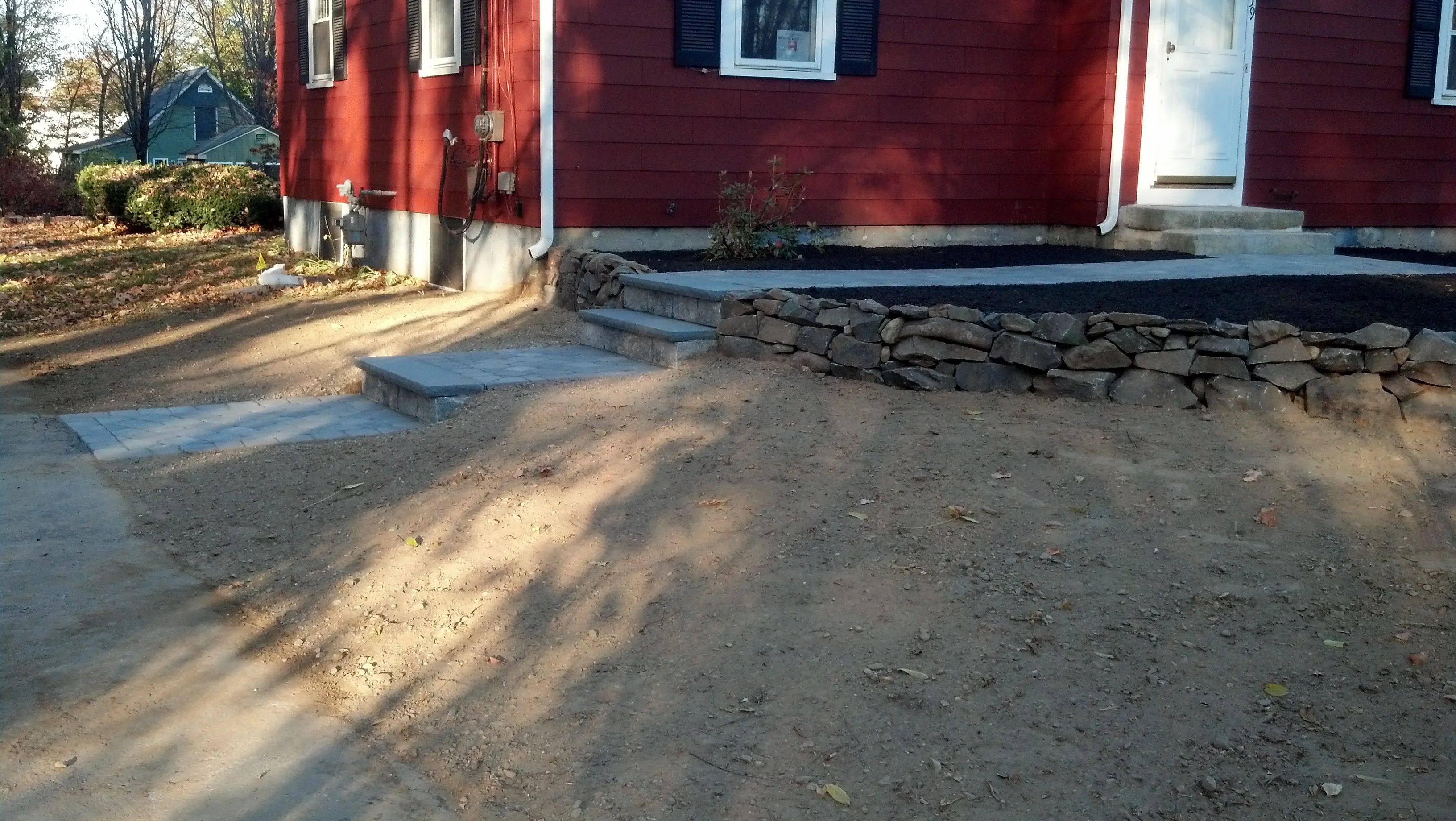 Dry-stacked stone retaining wall and concrete steps at residential foundation