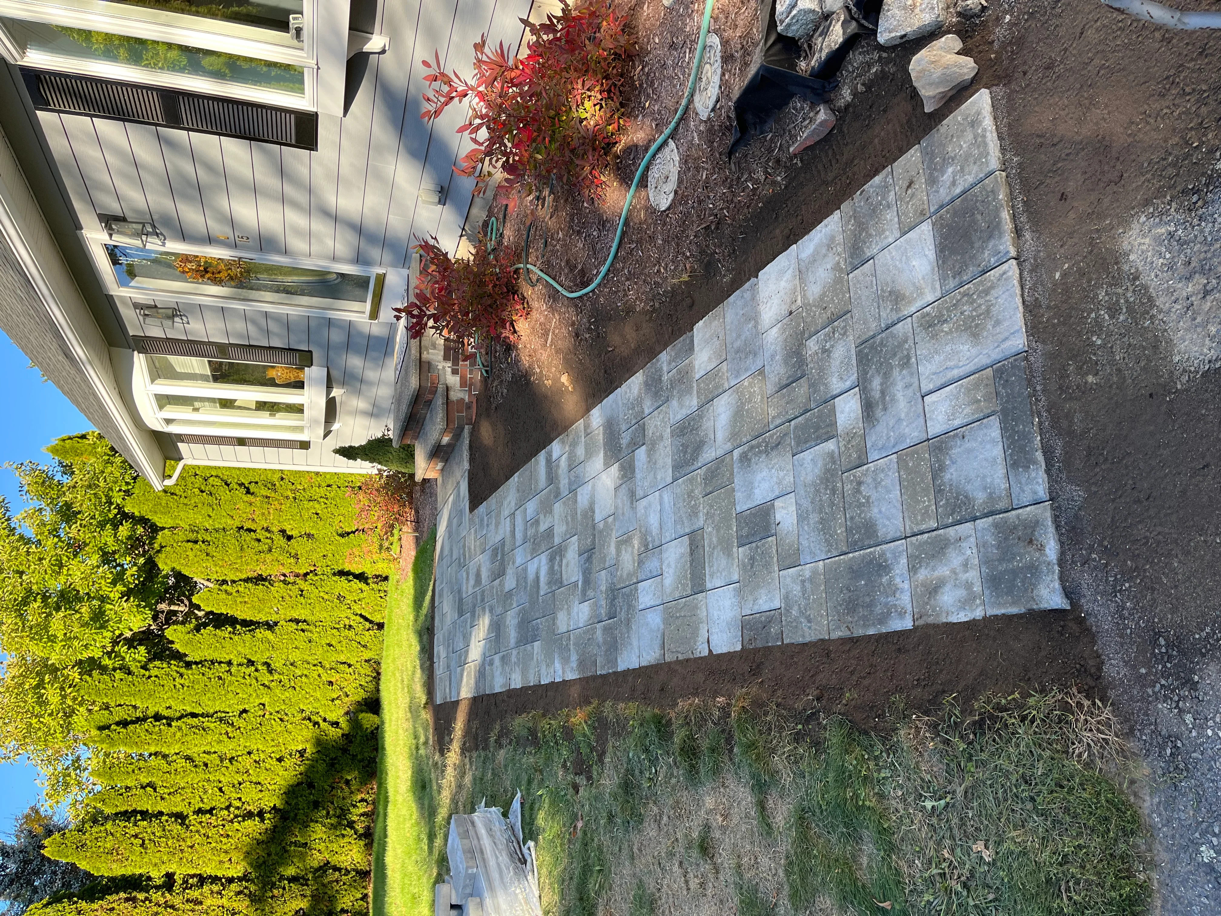Gray concrete paver patio with running bond pattern and stone edging installation