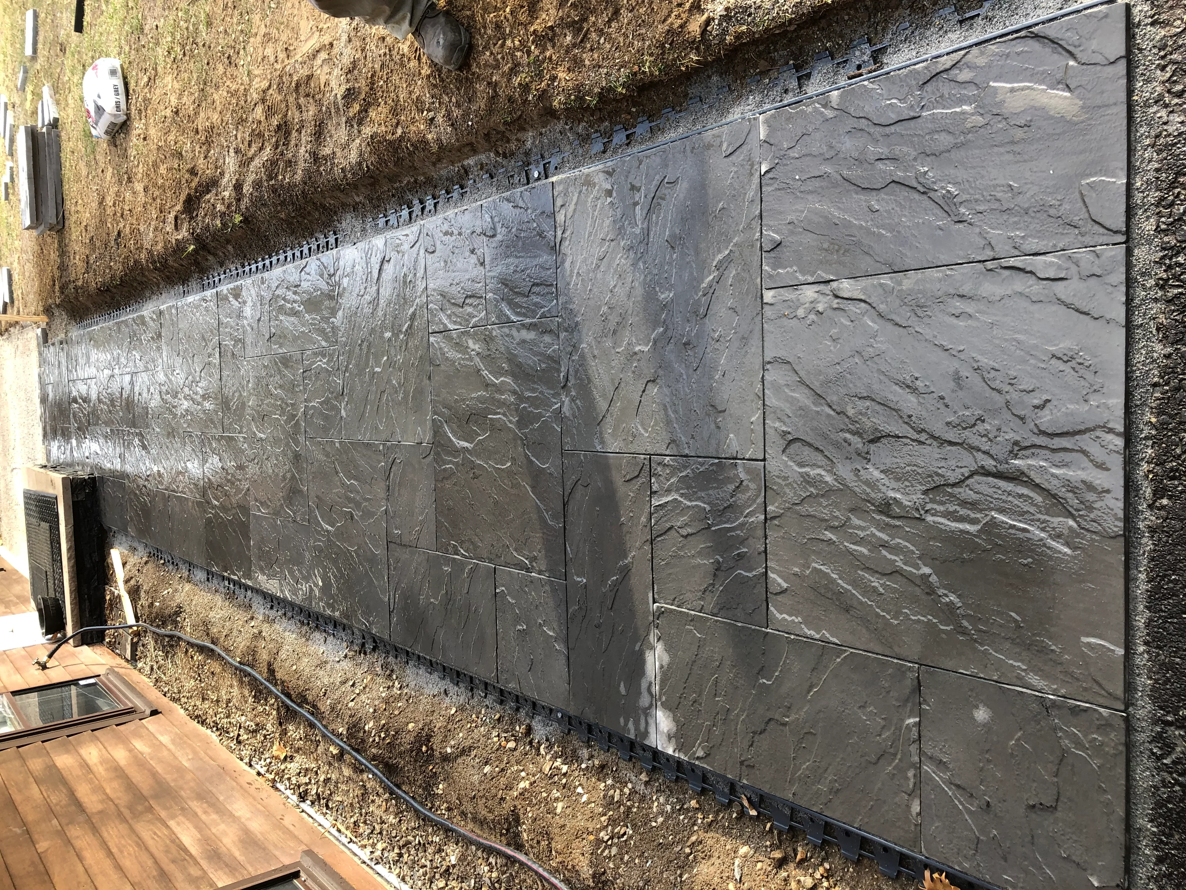 Dark gray textured slate veneer panels installed on foundation wall with grout lines
