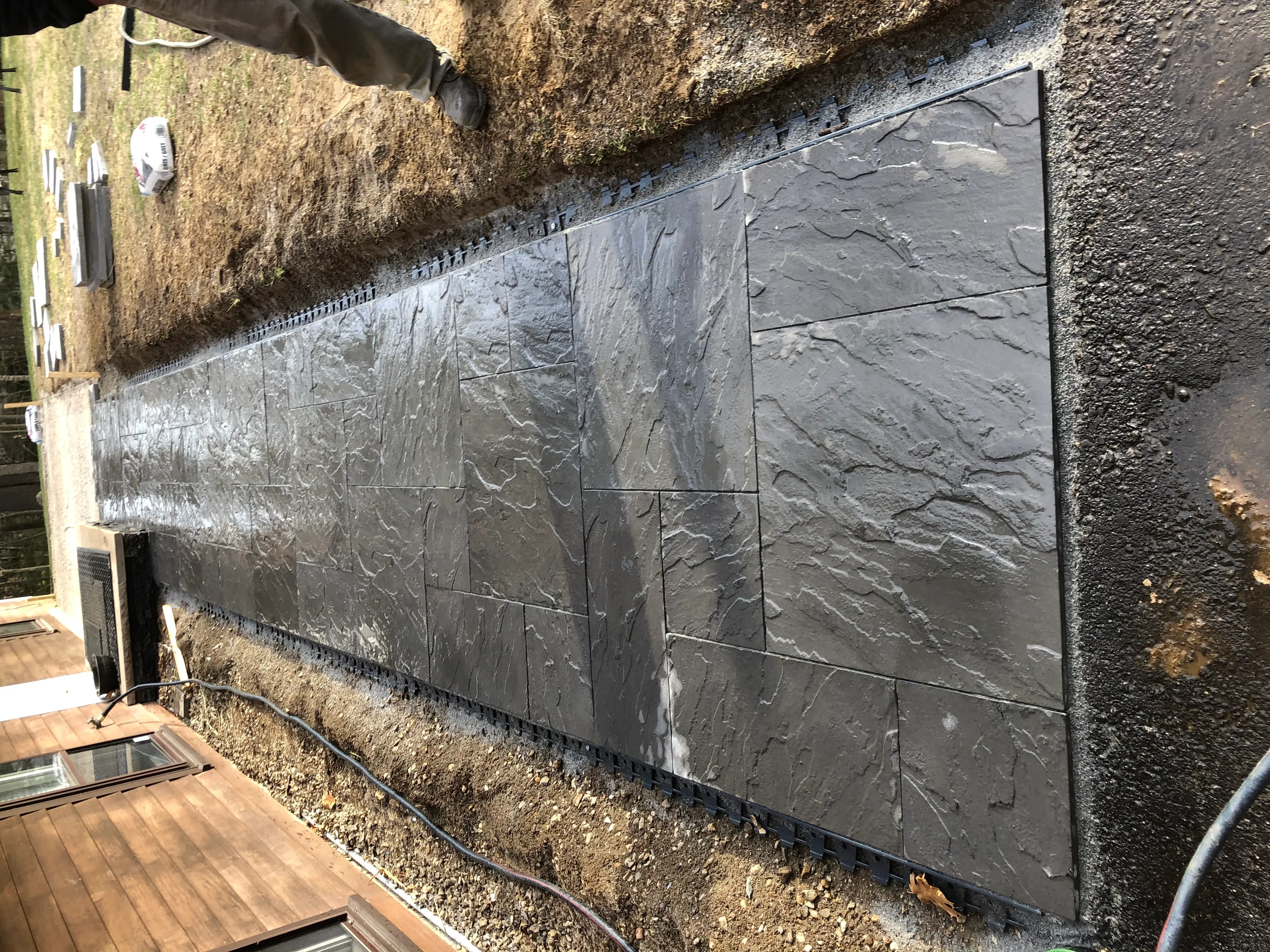Gray slate tile retaining wall with textured finish and metal trim edging