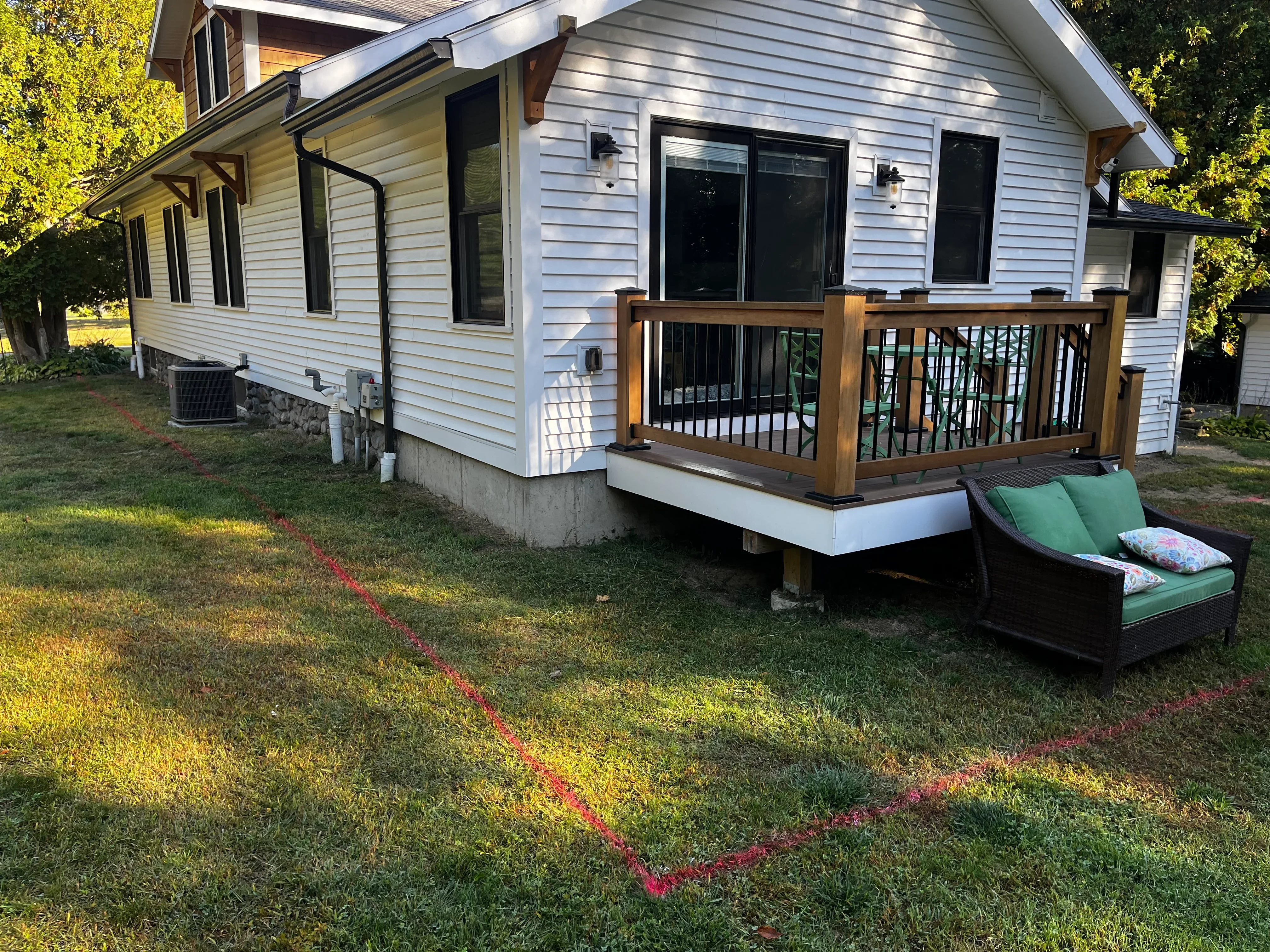 Two-level composite deck with wood and metal railings, concrete foundation, residential home exterior