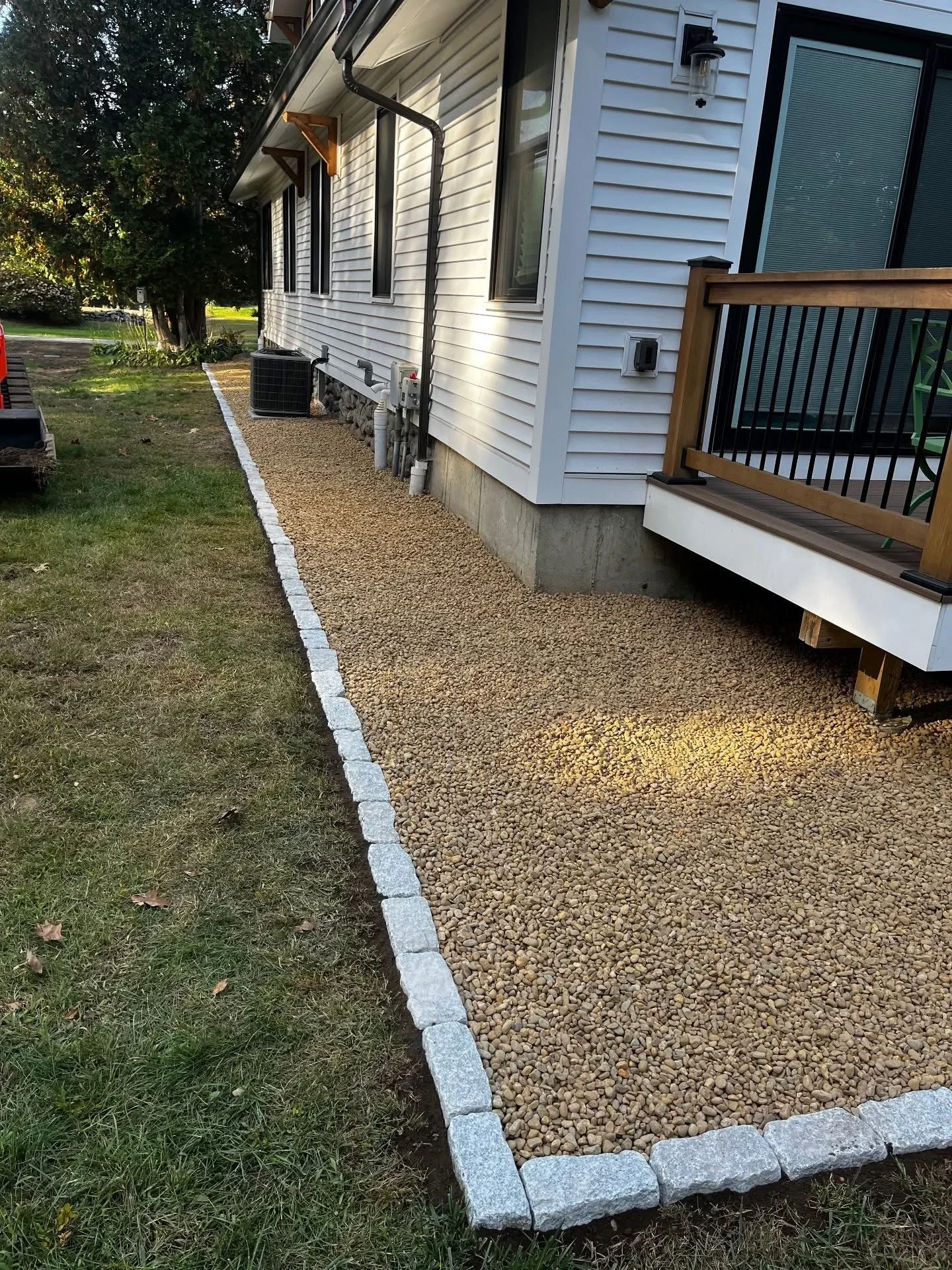 Tan gravel pathway with concrete block edging along residential home foundation