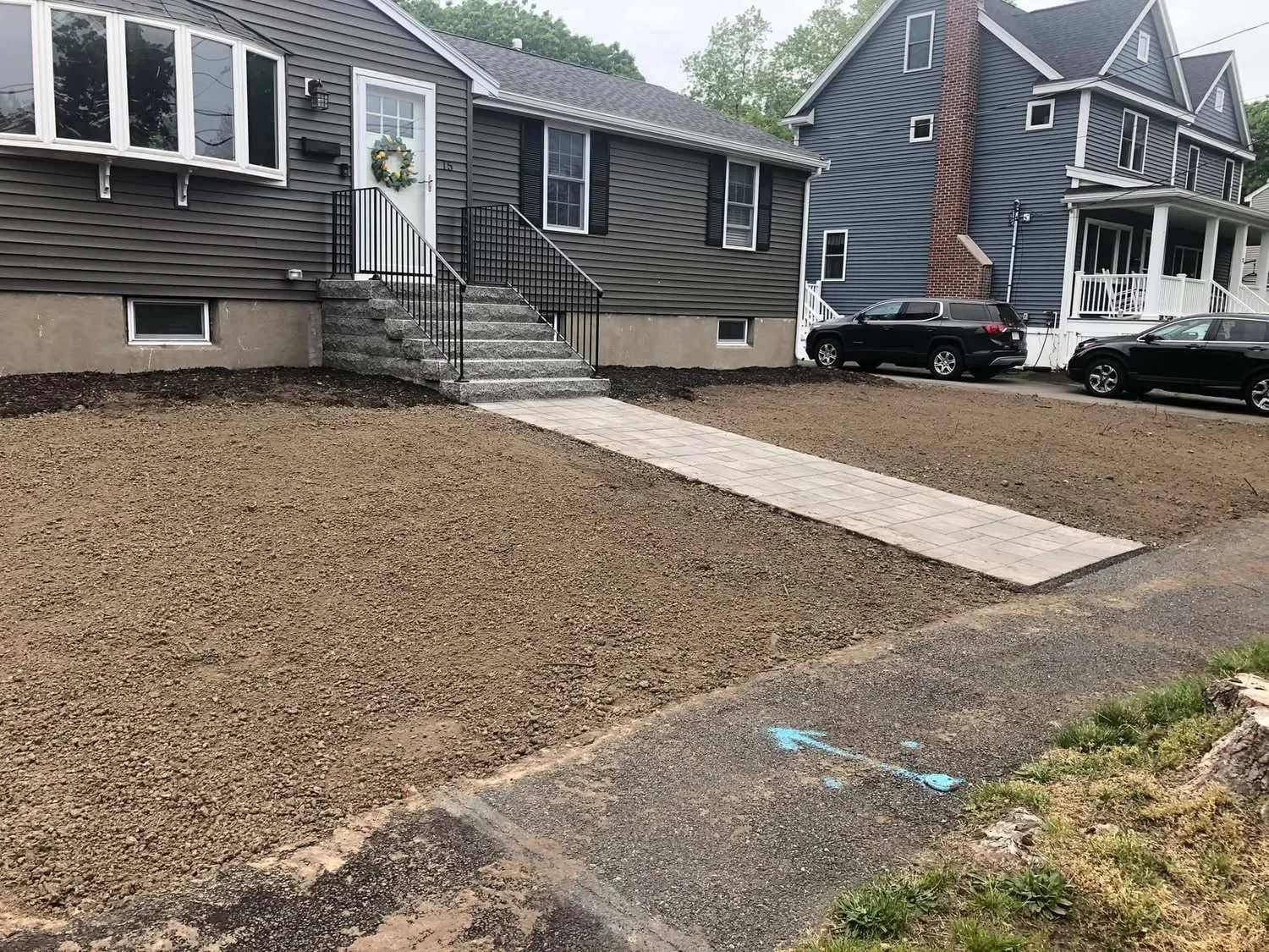 Graded front yard with new paver walkway and stone steps leading to residential entrance