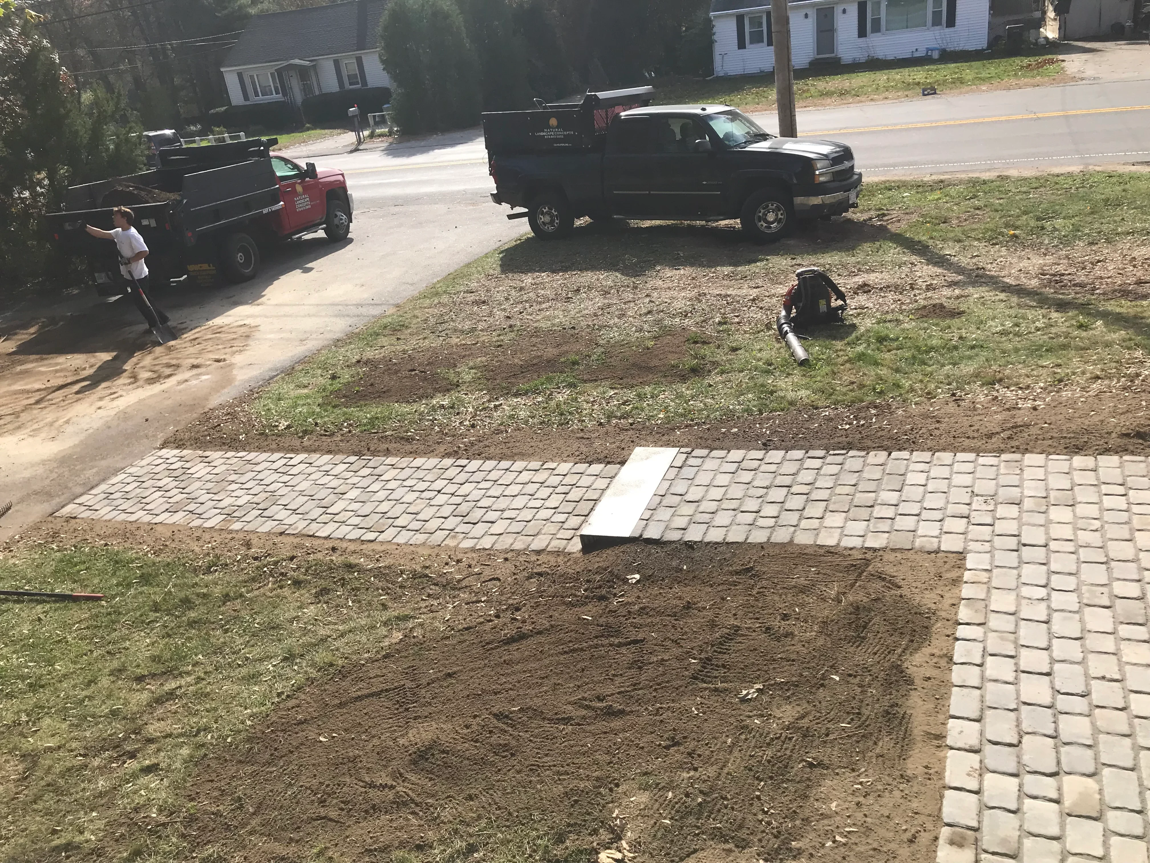 Concrete paver walkway installation in progress with prepared base and laid pavers