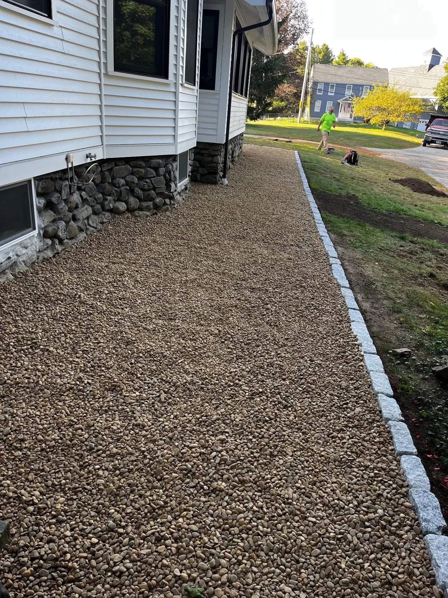 Gravel pathway with concrete edging along house foundation and stone veneer