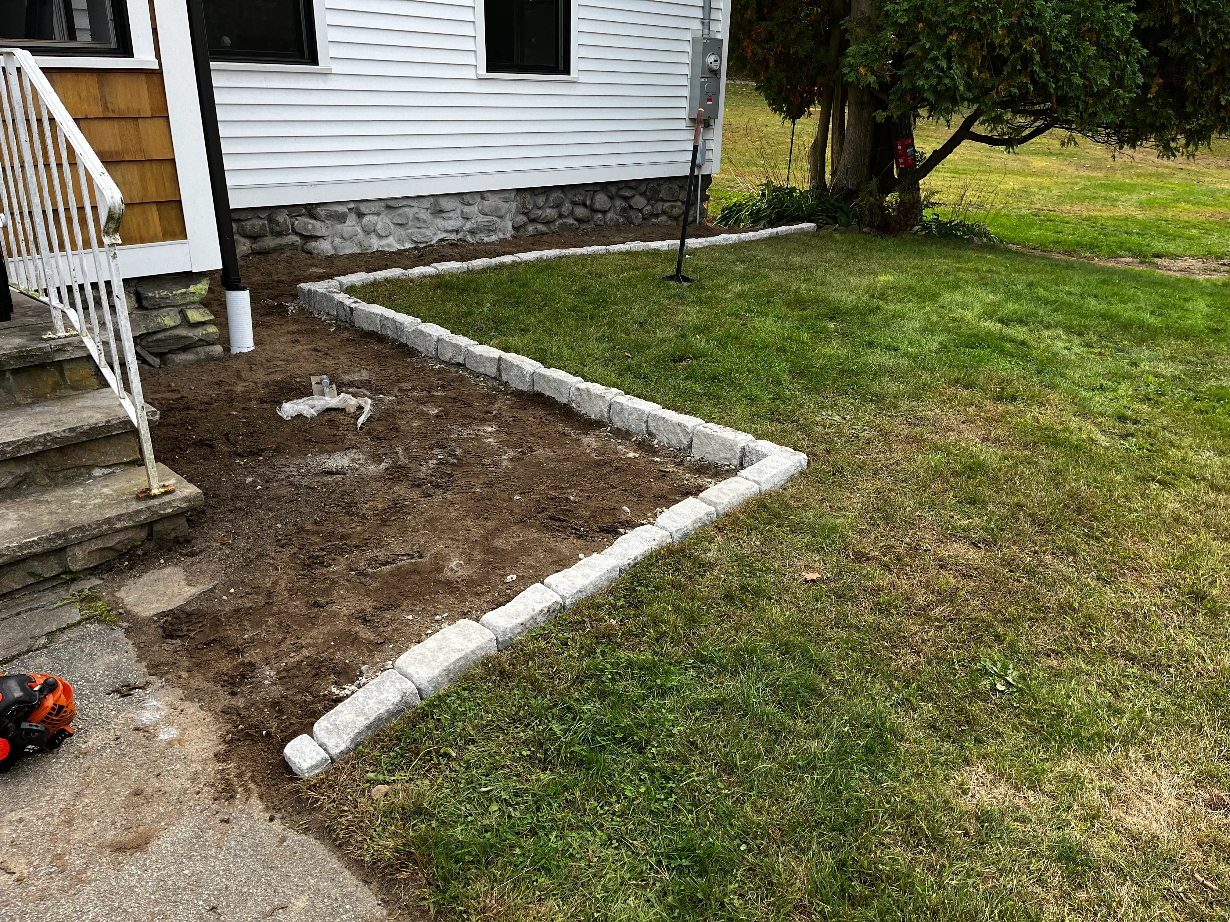 Concrete curb edging installed around prepared soil landscape bed with white border definition