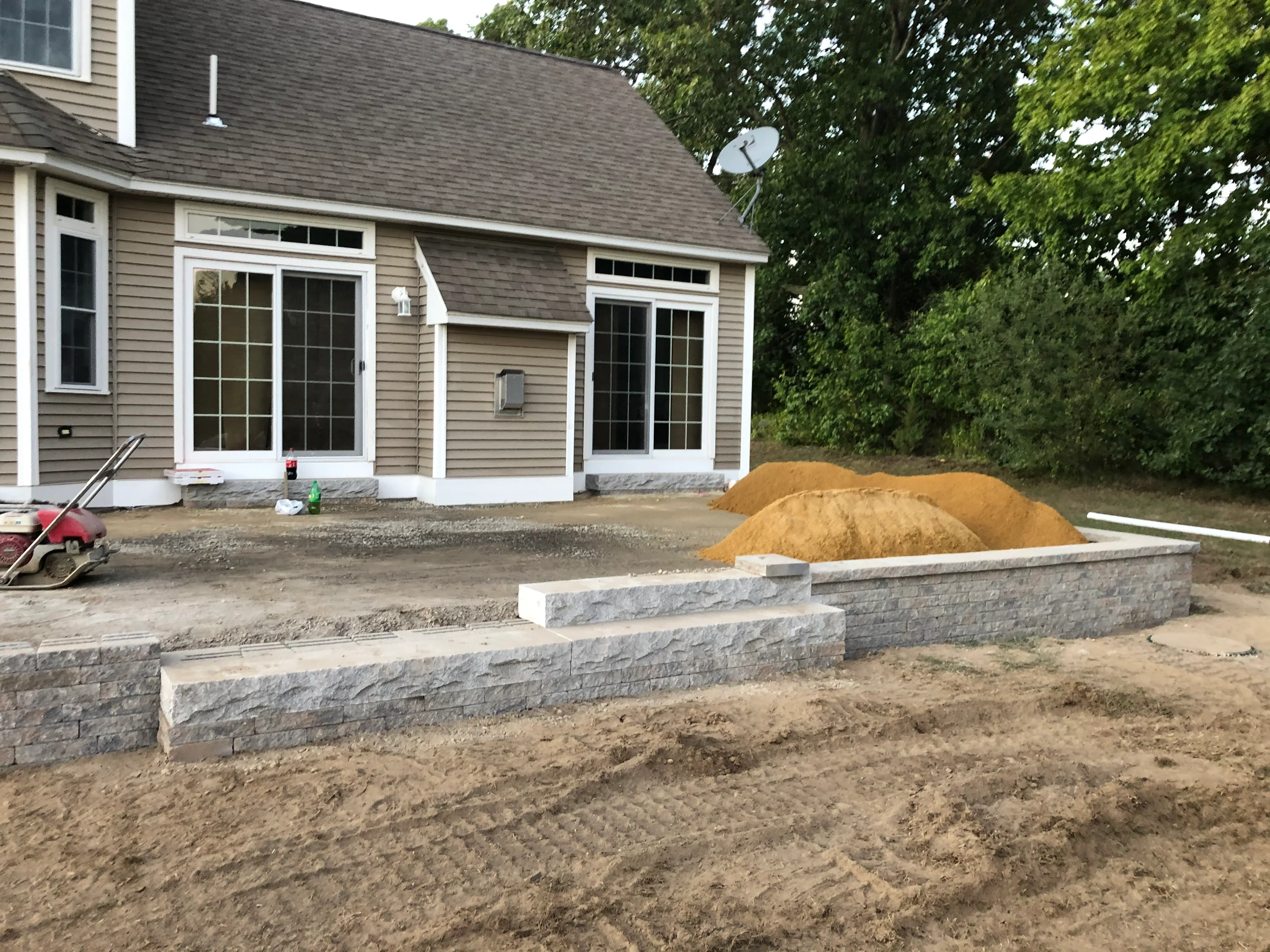 Stacked stone retaining walls with topsoil grading at residential home addition
