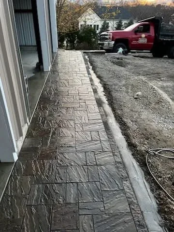 Stamped concrete walkway with slate pattern finish along residential home foundation