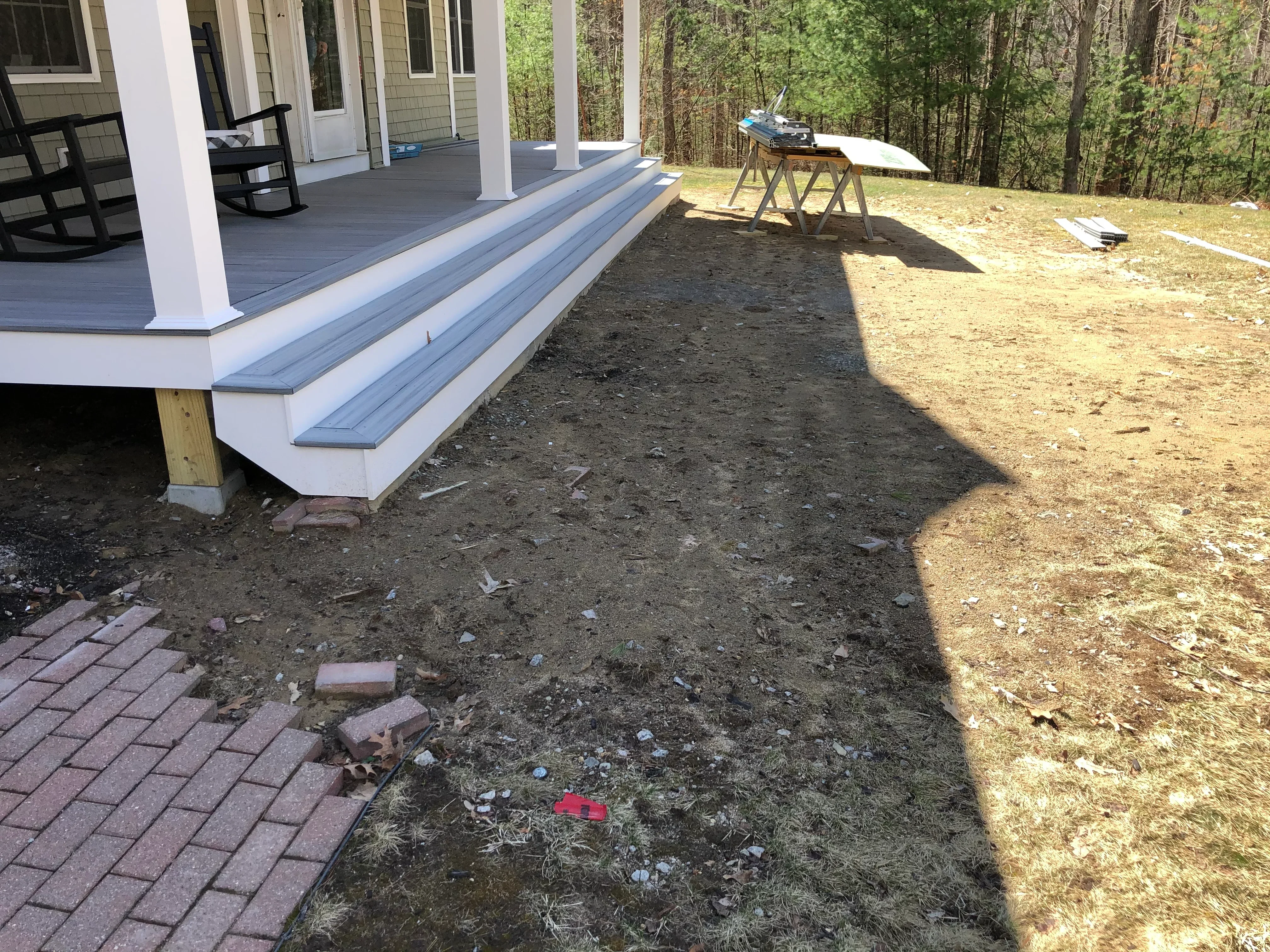 Composite deck with white trim and graded dirt yard during landscape construction