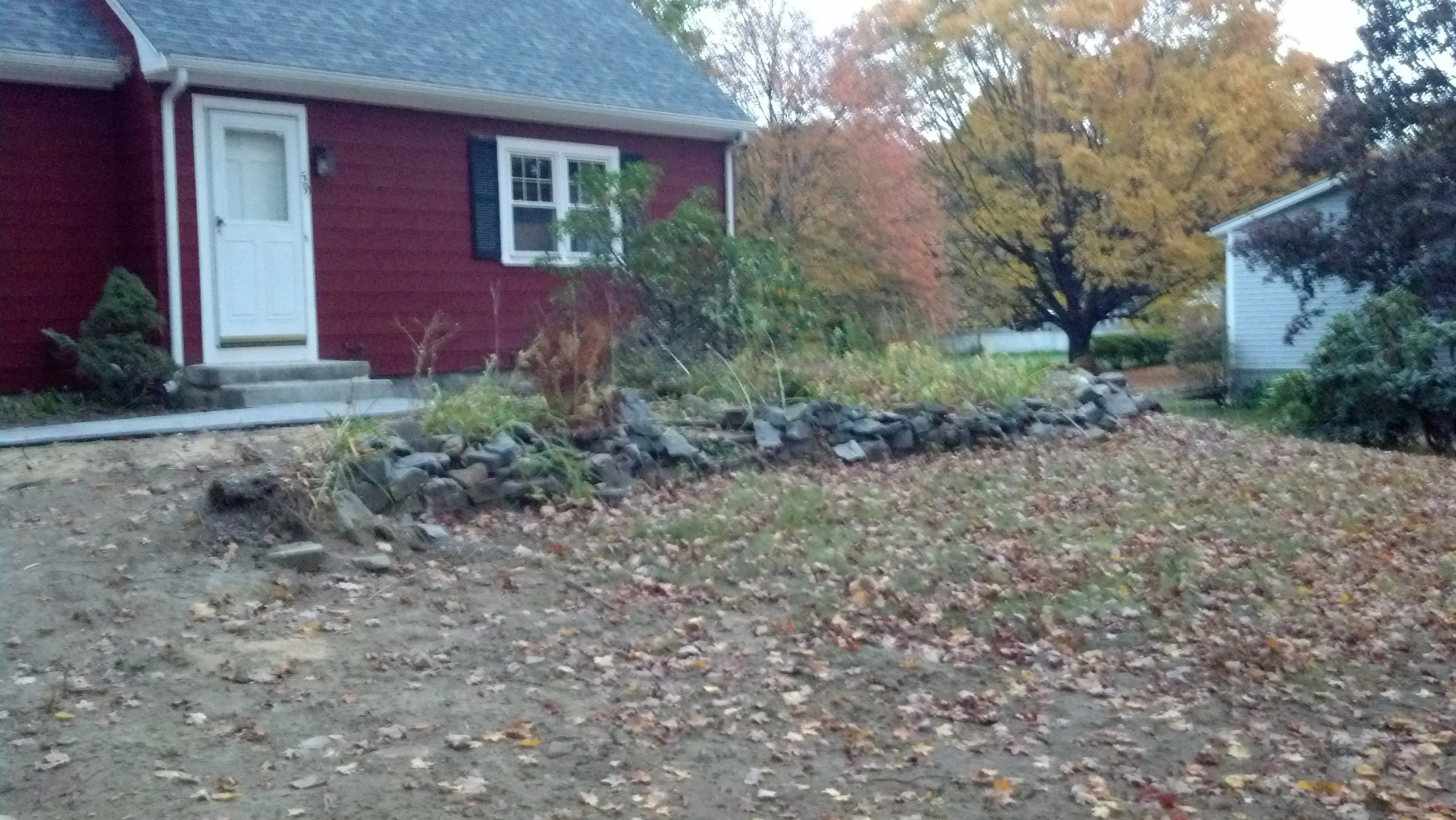 Stone-edged landscape bed with mulch and shrub plantings along residential home foundation