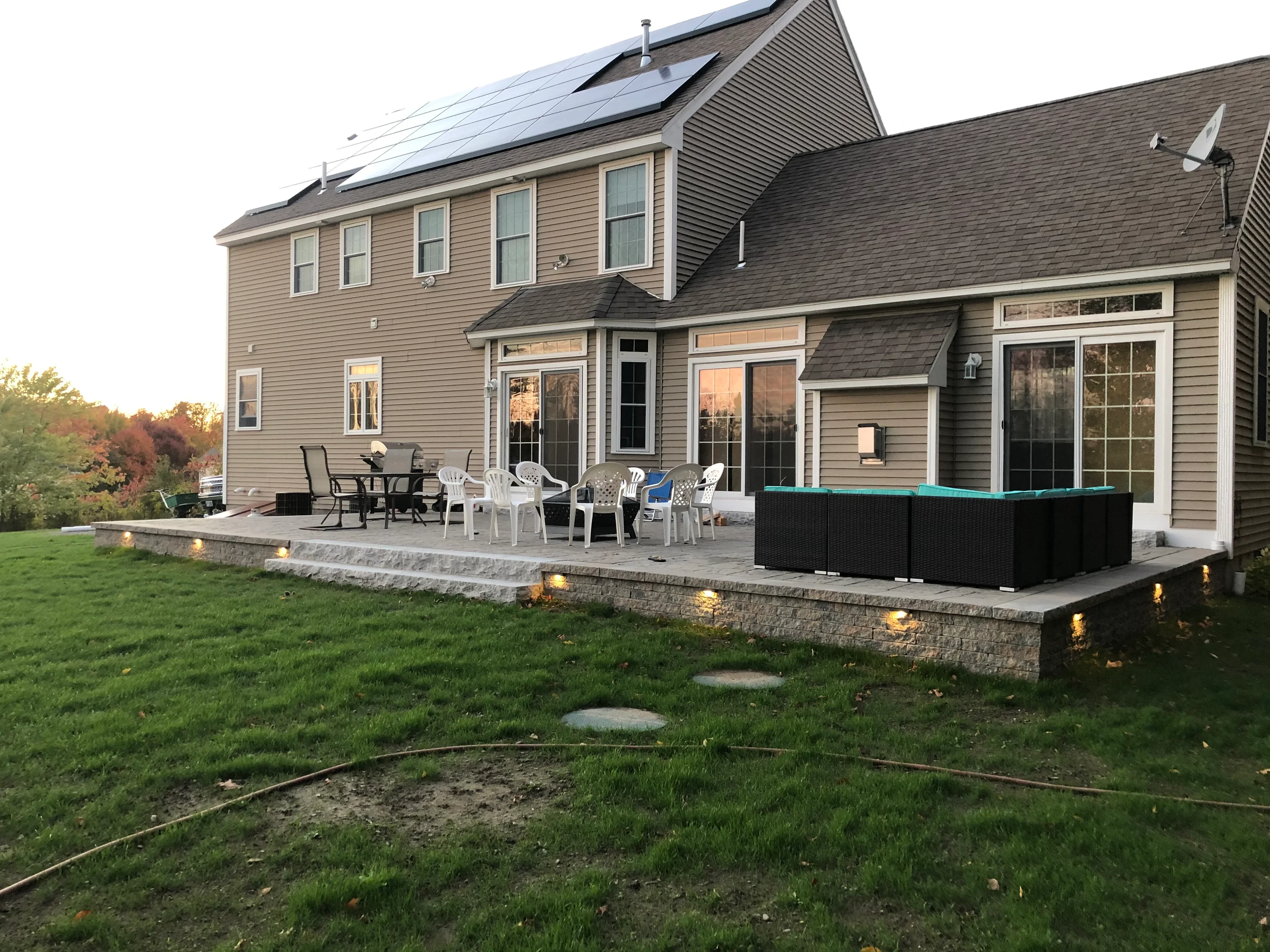 Stone retaining wall patio with LED lighting, composite decking, and tiered landscaping