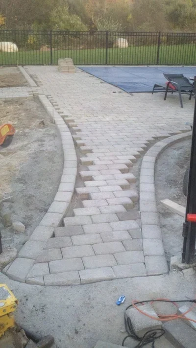 Curved concrete paver patio with decorative stone border and running bond pattern