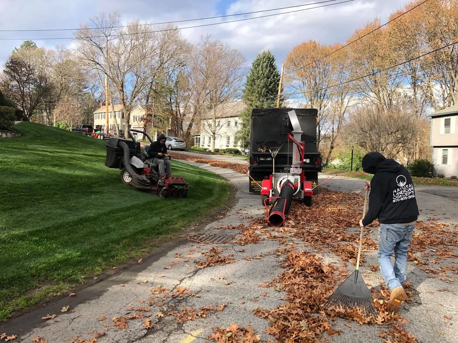 Fall leaf cleanup with wood chipper and debris trailer on residential driveway