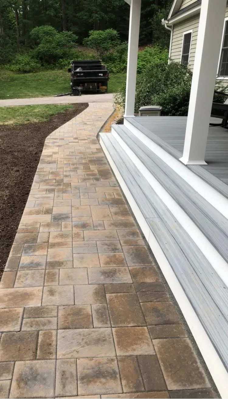 Herringbone paver walkway with tumbled stone pavers in tan and brown tones alongside home