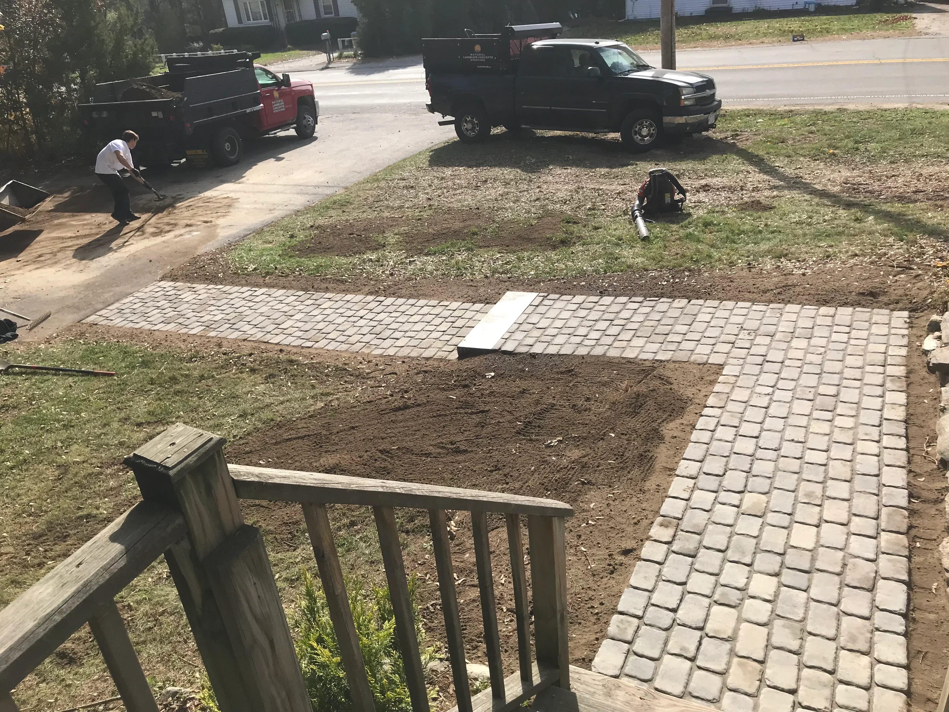 Tan permeable pavers being installed in running bond pattern on prepared base with workers and equipment on site