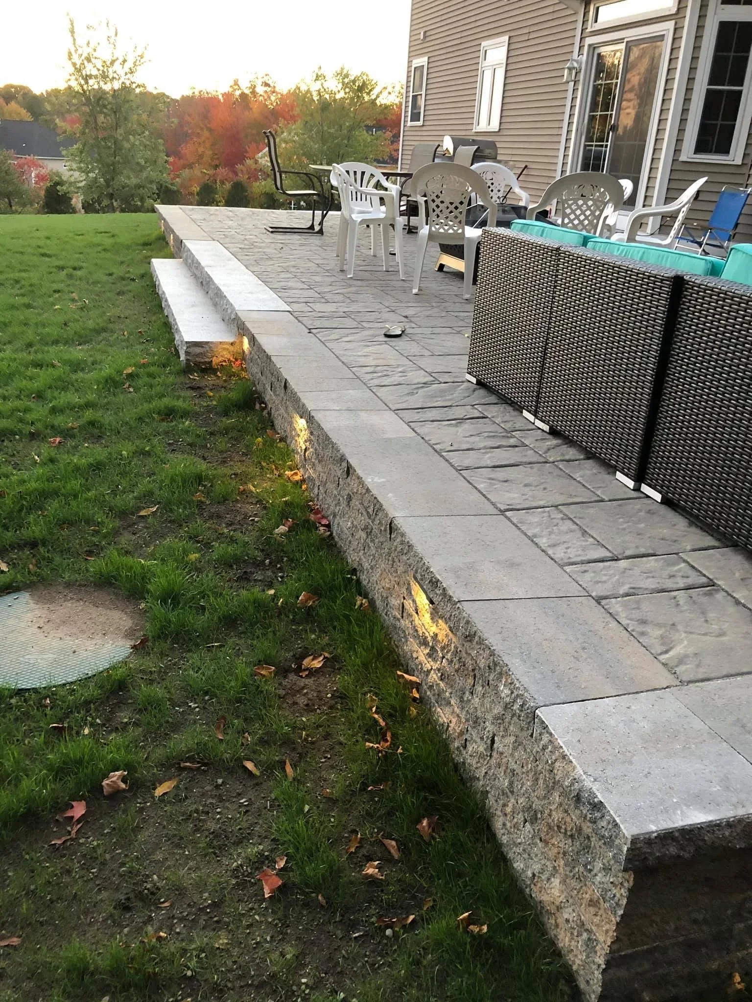 Stone paver patio with retaining wall and seating area overlooking lawn